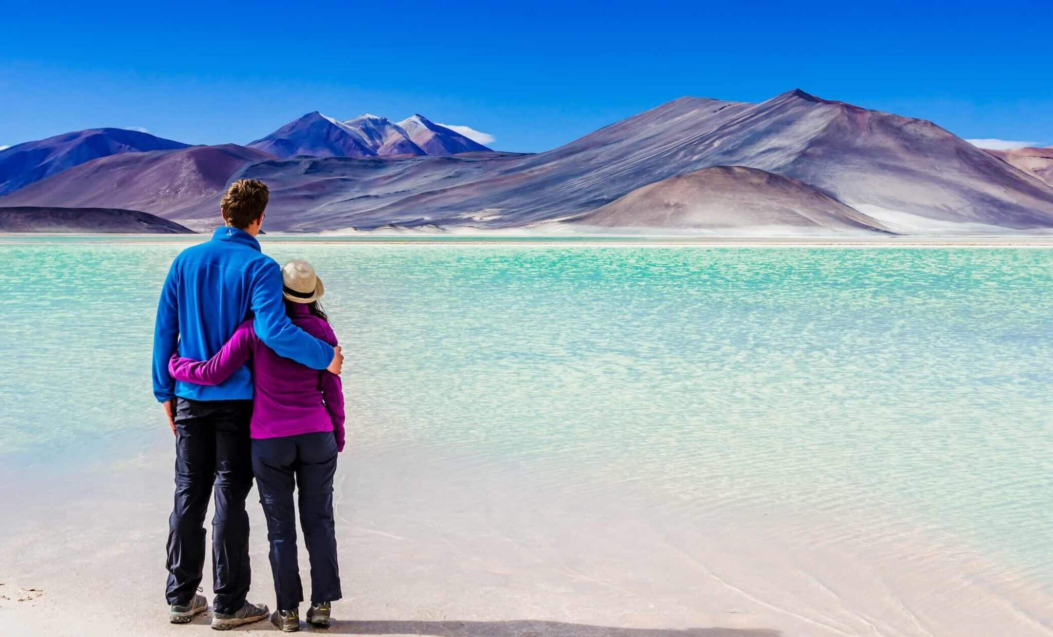 Couple enjoying view on Laguna Salar de Talar with the Andes Mountain, San Pedro de Atacama, Chile